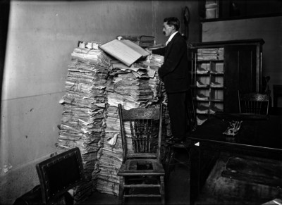 Hombre lee sobre una pila de libros de un archivo