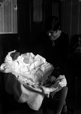 Mujer mostrando prendas pequeñas de tela bordadas, en un canasto