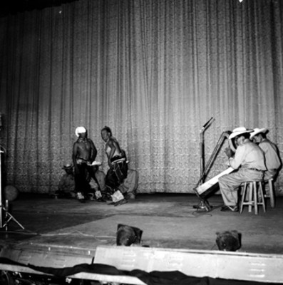 Hombres interpretando una danza y músicos en el Teatro Iris, durante el festival en honor a Adolfo López Mateos
