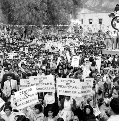 Adolfo López Mateos y mujer ataviada de china poblana, observando un mitin en Galeana