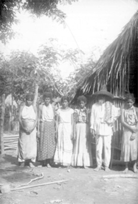 Grupo de indígenas al lado de un jacal de palma