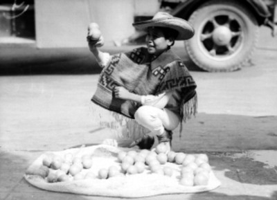 Niño vendiendo fruta en la acera de una calle