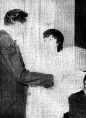 Pareja de artístas conversando sosteniendo un documentos en las manos en un salón