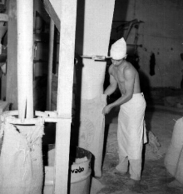 Trabajador con máquina llenando costales de arroz en un molino de Culiacán