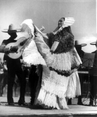 Mujer vestida de tehuana canta durante un evento