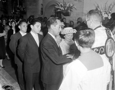 Sacerdote y gente durante ceremonia religiosa en el interior de una iglesia