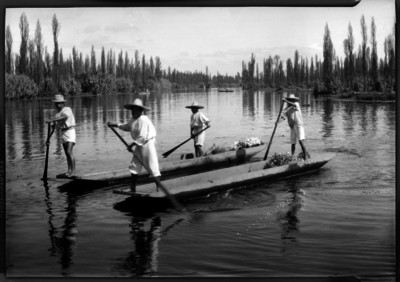Hombres transportan flores en sus canoas por un canal de Xochimilco