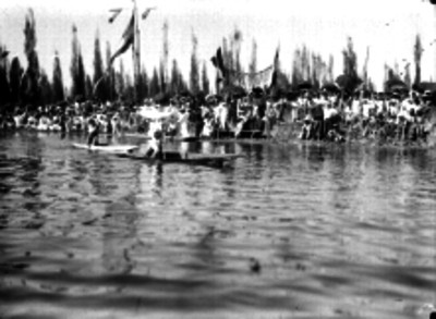 Gente a la orilla de un canal de Xochimilco durante una carrera de canotaje