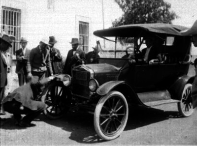 Hombre revisando la llanta de un auto fuera de la Agencia Robertson Motor Co. S.A.