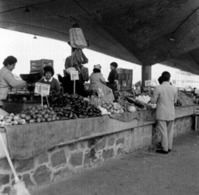 Compradores y vendedores en un puesto de verduras del mercado de Jamaica