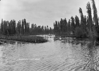 Hombres abordo de canoas navegan en el canal de Xochimilco