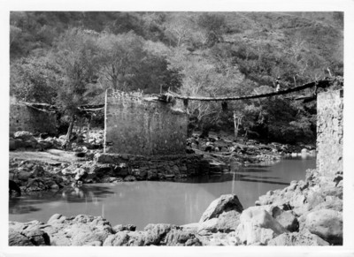 Hombre con canasta en mecapal en un puente de madera