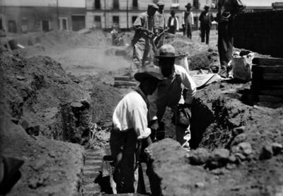Albañiles colocan ladrillos en una zanja
